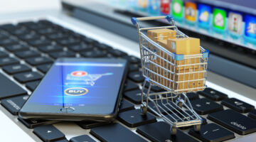 Online shopping, internet purchases and e-commerce concept, modern mobile phone with buy button on the screen and shopping cart full of package boxes on computer laptop keyboard